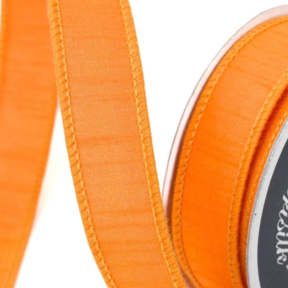 Close-up of orange wired ribbon with faux dupioni texture for wreaths and DIY decor.